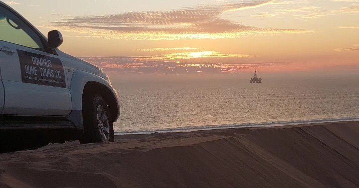 4x4 vehicle driving through massive red dunes at Sandwich Harbour, Namibia adventure tour